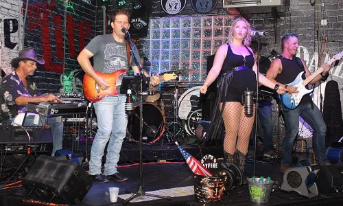 Band performs live onstage with two lead singers at front.