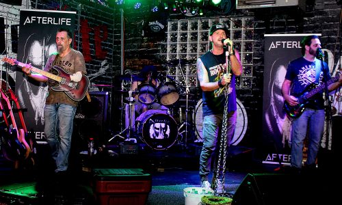 Band performs live onstage under green and purple lights.