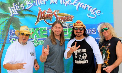 Four men pose in front of a Main Street festival banner.