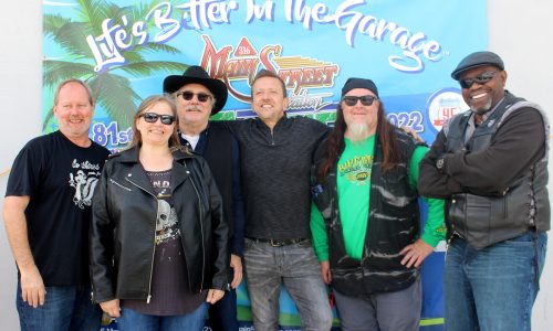 Six people pose in front of a ‘Life’s Better in the Garage’ banner.